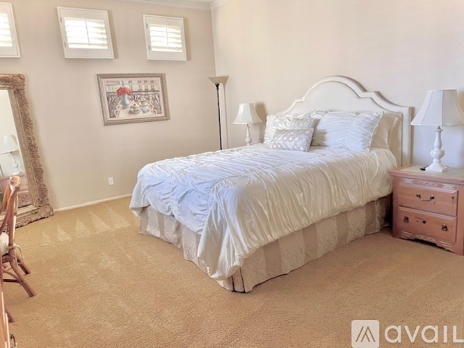 A bedroom with a large bed, a dresser, and a mirror.