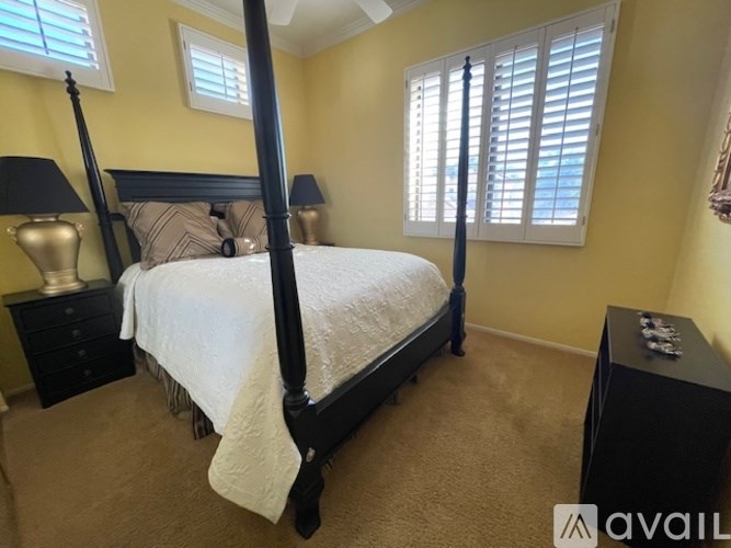 A bedroom with a four poster bed and a window with blinds.