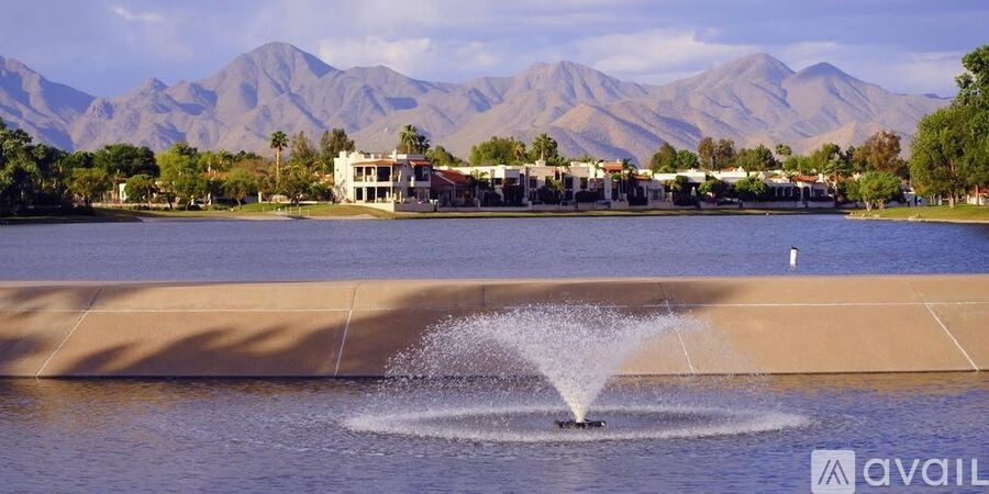 A fountain in the middle of a lake with mountains in the background.
