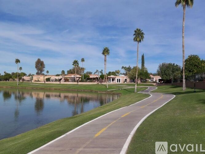 A pathway runs alongside a body of water with palm trees in the background.