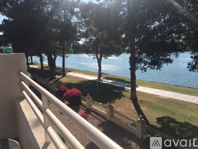 A view from a balcony overlooking a lake with trees and a white fence.