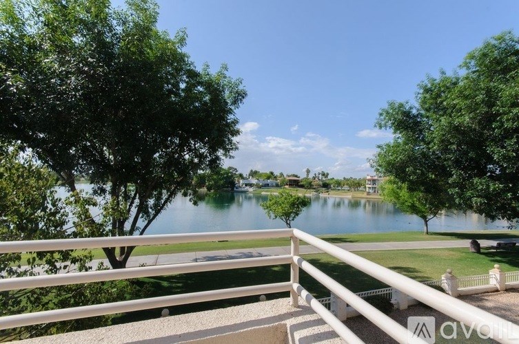 A serene view of a lake with a white railing in the foreground.