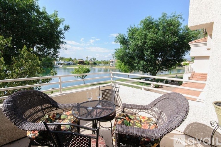A balcony with two chairs and a table overlooking a body of water.