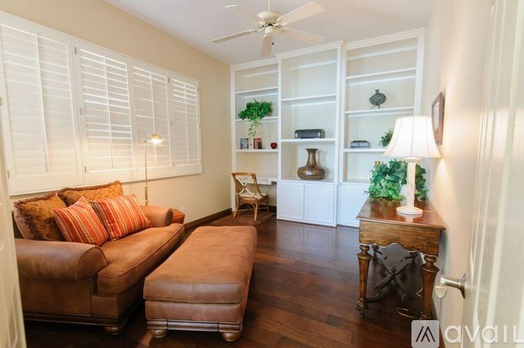 A living room with a brown leather couch and a brown ottoman.