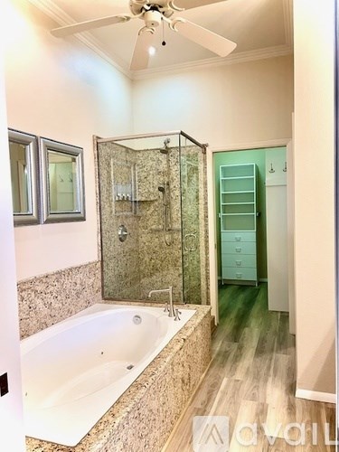 A bathroom with a bathtub, shower, and a ceiling fan.