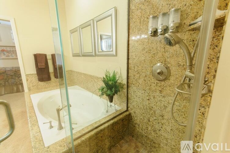 A bathroom with a glass shower door and a plant in the shower.
