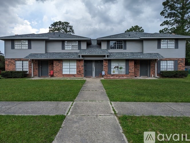 A two-story house with a brick facade and a grey roof.