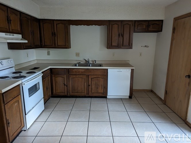 A kitchen with white appliances and brown cabinets.