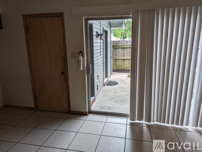 A room with a wooden door and a sliding glass door leading to a backyard.