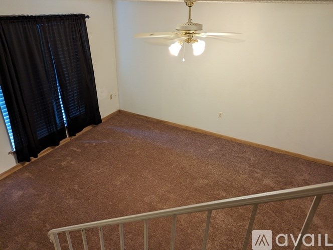 A room with a ceiling fan and a carpeted floor.