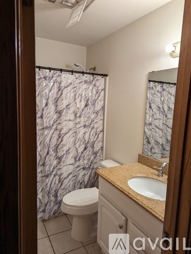 A bathroom with a marble shower curtain and a white toilet.