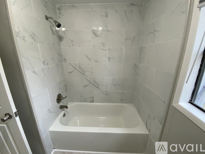 A white bathtub in a bathroom with marble tiles.
