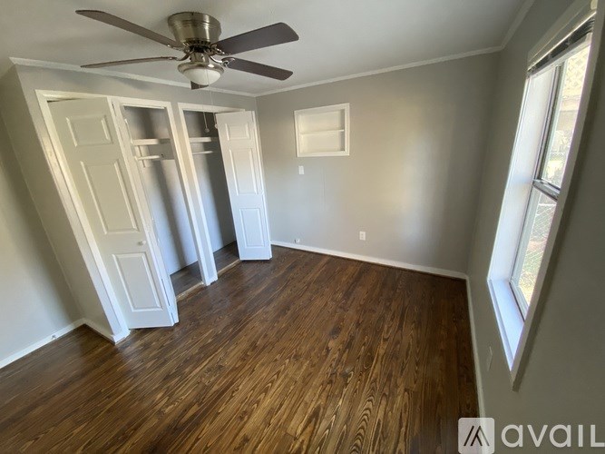 A room with a ceiling fan and wooden flooring.