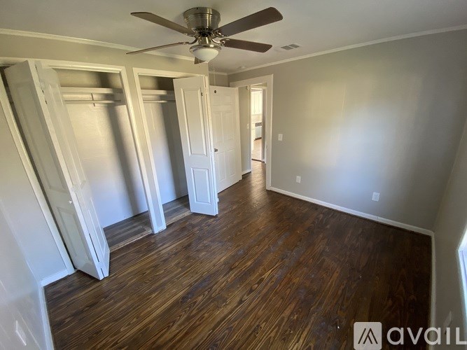 A room with a ceiling fan and wooden flooring.