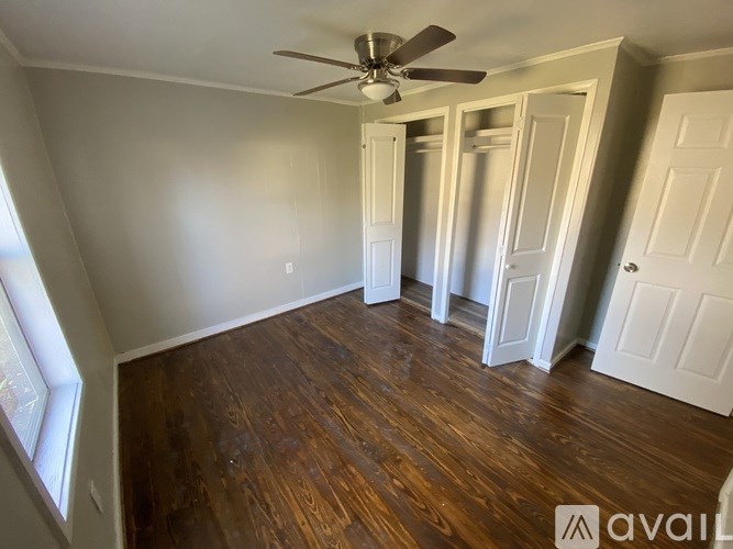 A room with a ceiling fan and wooden flooring.