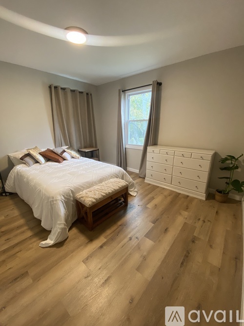 A bedroom with a large bed and wooden flooring.