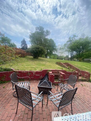 Four black metal chairs are arranged in a circle on a brick patio.
