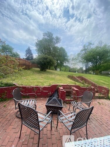 Four black metal chairs are arranged in a circle on a brick patio.