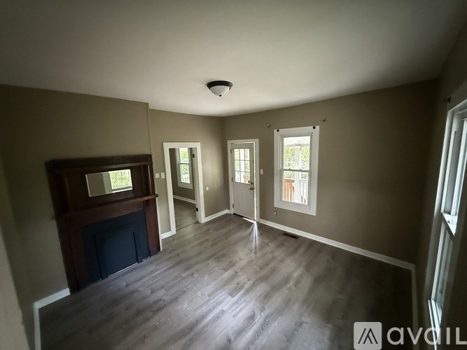 A room with a fireplace and three windows.