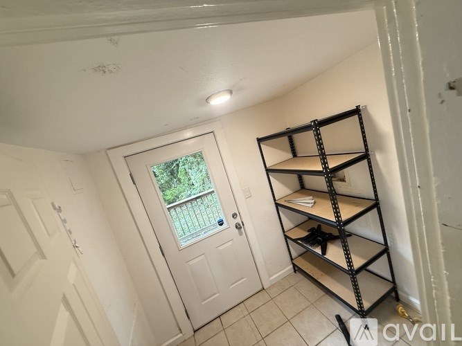 A white door with a glass window is in a room with a shelving unit.
