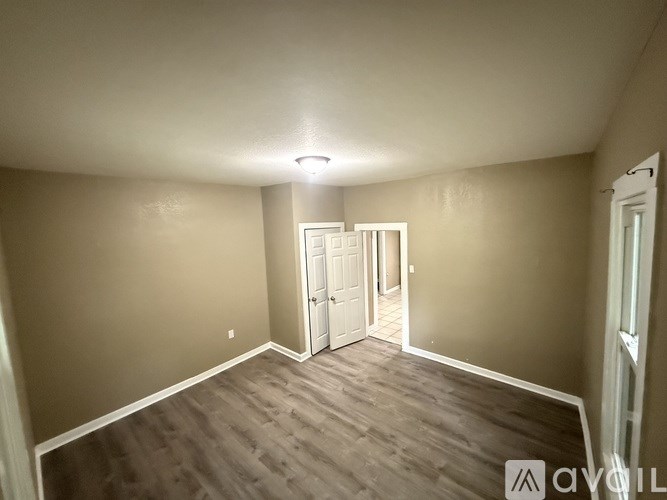 A room with a wooden floor and a white ceiling with a light fixture.