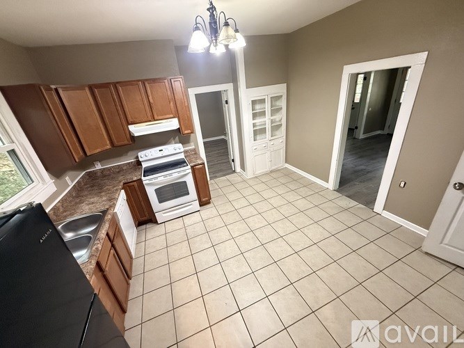 A kitchen with brown cabinets and a black dishwasher.
