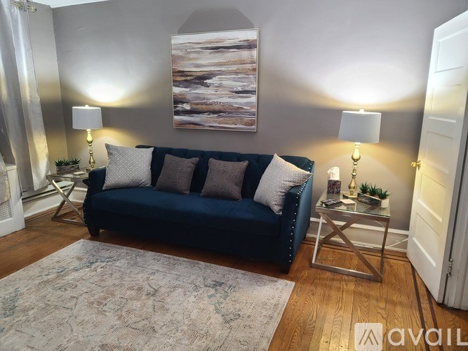 A living room with a blue couch and a painting on the wall.