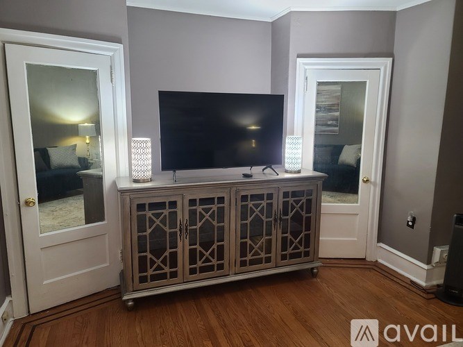 A room with a tv on a cabinet and a door on the left.