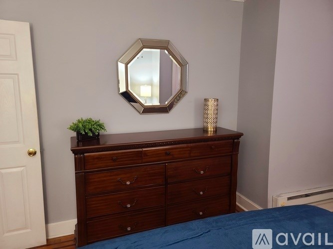 A bedroom with a wooden dresser and a mirror above it.