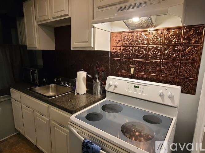 A white stove top oven with four burners is in a kitchen with white cabinets.