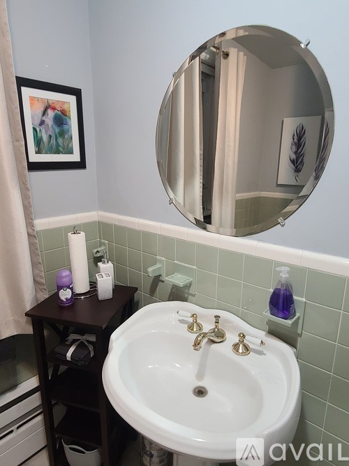 A bathroom with a white sink and a round mirror.