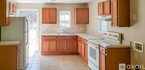 A kitchen with brown cabinets and white appliances.