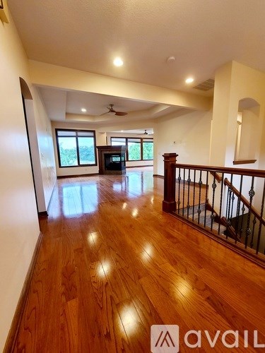 A spacious living room with wooden floors and a staircase.