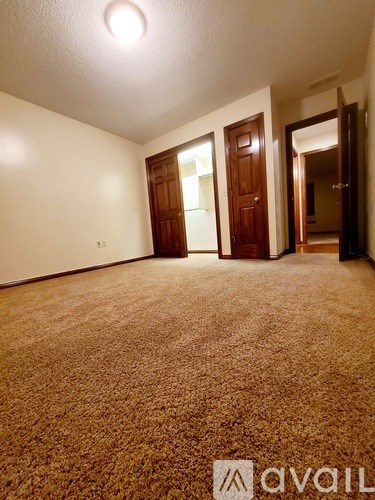 A carpeted room with a door and a mirror.