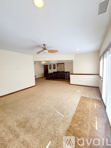 A room with a carpeted floor and a ceiling fan.