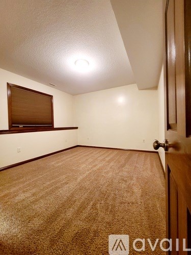A room with a carpeted floor and a door on the right side.