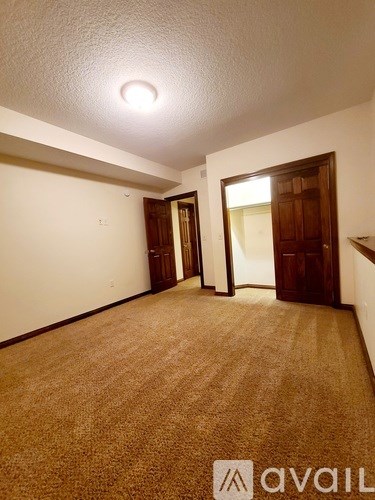 A carpeted room with a door on the right and a window on the left.