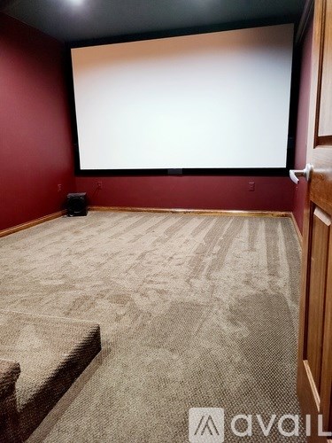 A room with a carpeted floor and a large screen on the wall.