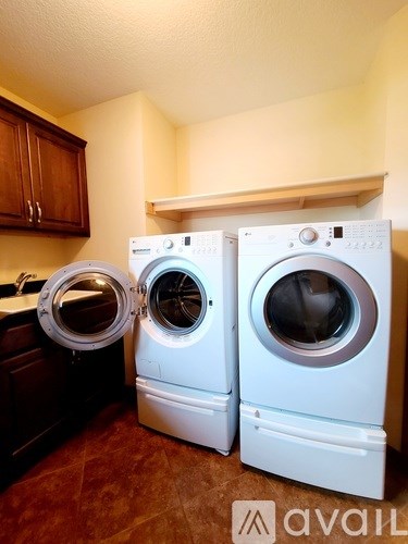 Two white front loading washing machines in a laundry room.