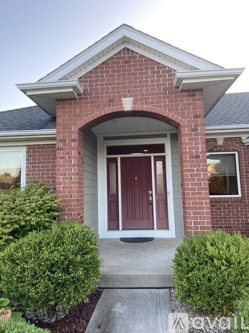 A red brick house with a red door and a small window on the side.
