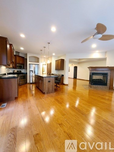 A spacious kitchen with wooden floors and a ceiling fan.