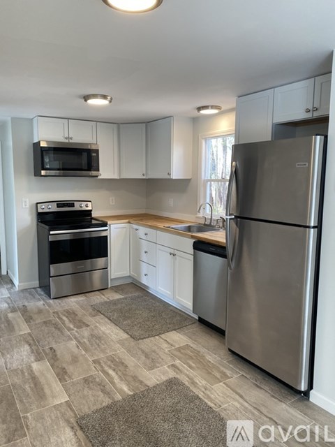 A kitchen with a refrigerator, microwave, oven, and sink.