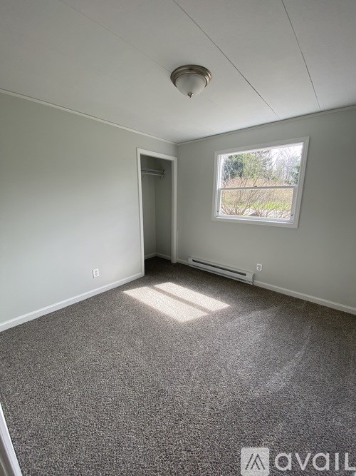 A room with a carpeted floor, a window, and a door.