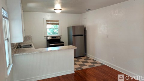 A kitchen with a refrigerator, sink, and a window.