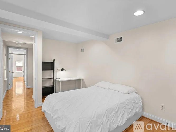 A bedroom with a bed, a desk, and a ceiling fan.