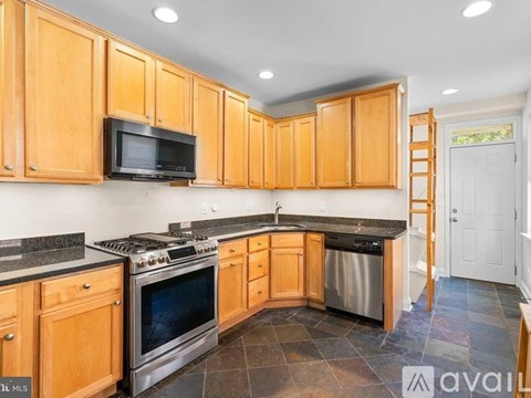 A kitchen with wooden cabinets and a black microwave above the stove.