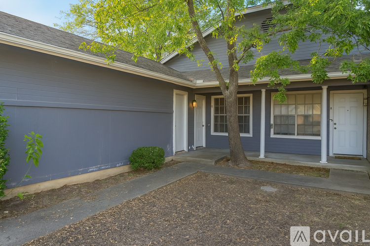 A house with a blue exterior and a tree in front.