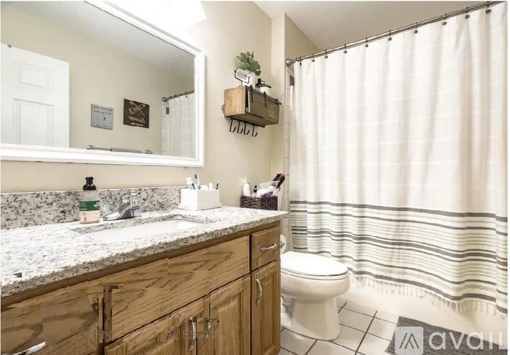 A bathroom with a white toilet, wooden cabinets, and a striped shower curtain.