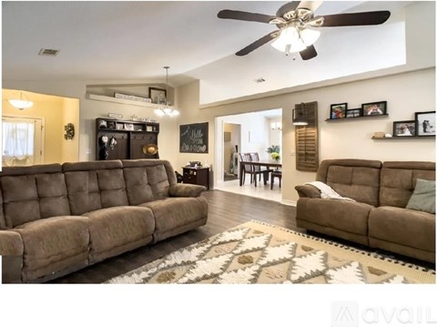 A living room with a brown sofa and a ceiling fan.