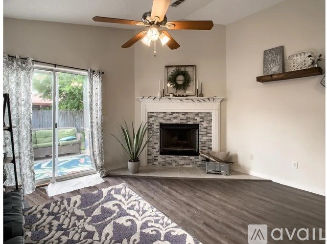 A living room with a fireplace and a ceiling fan.